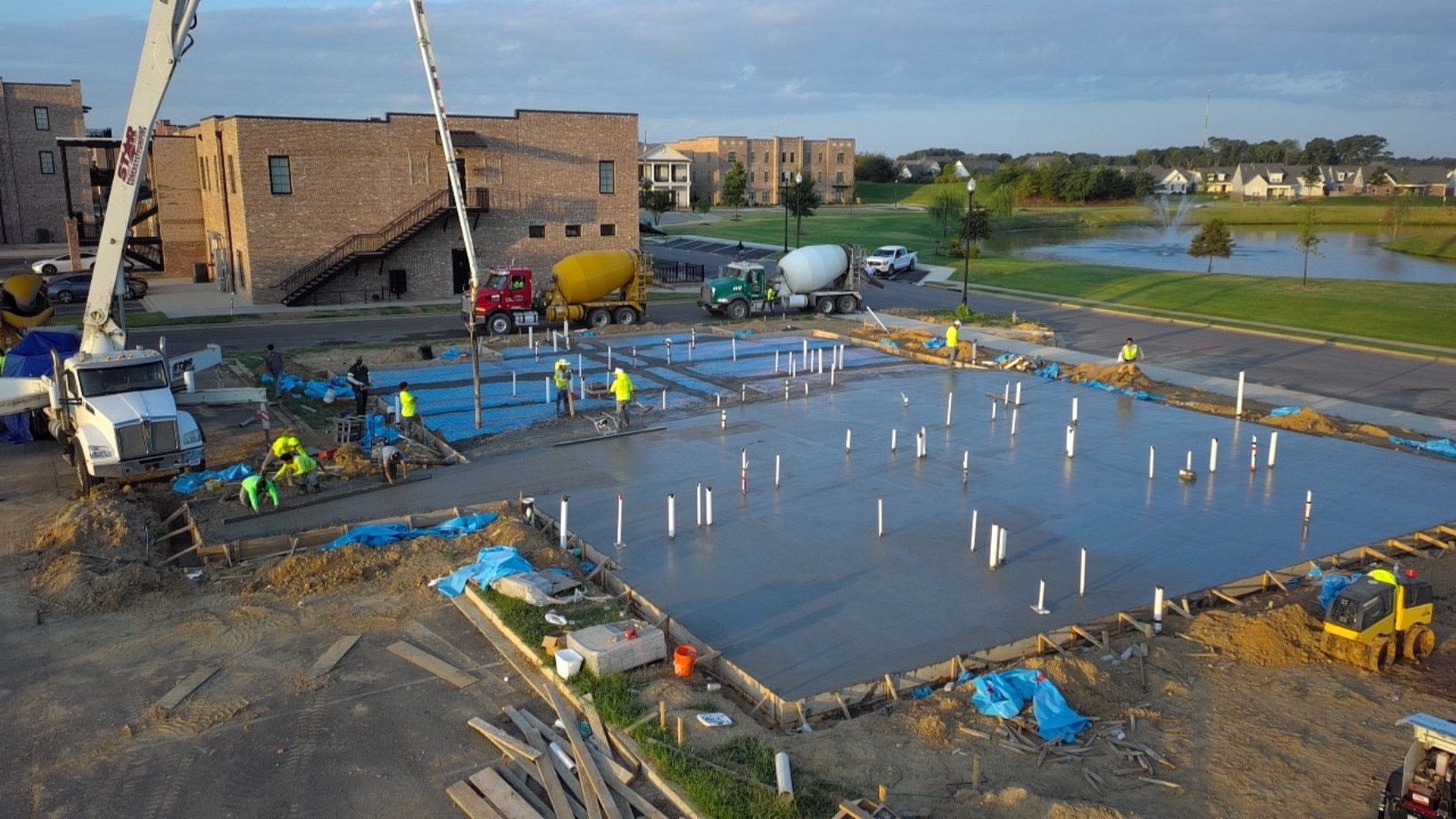 Aerial view of the M&M Concrete Services crew and pump trucks finishing a large freshly poured commercial foundation slab