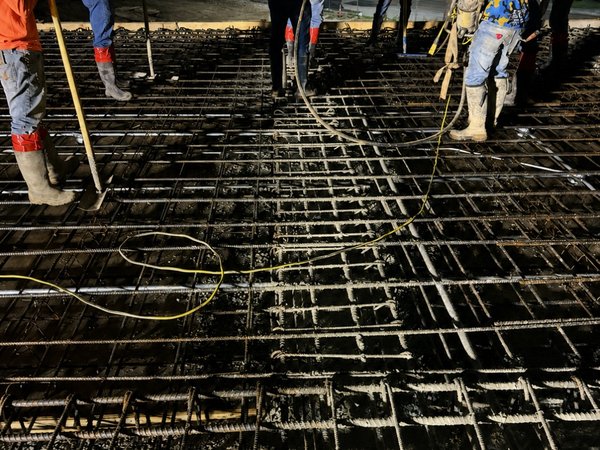 Crew finishing a freshly placed concrete slab at night under work lights on the Youth Villages jobsite