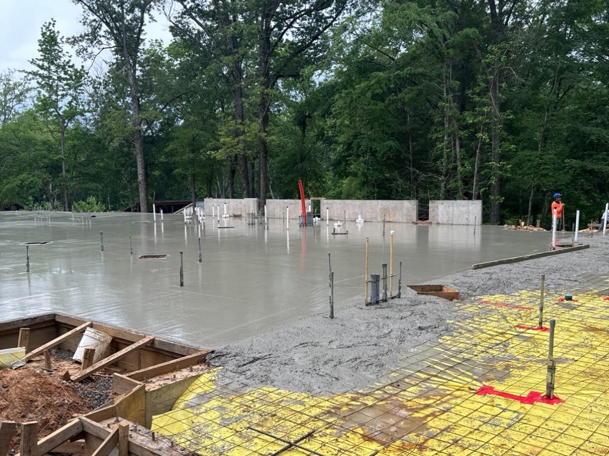Concrete slab pour in progress on the Youth Villages Dogwood Cottage campus, with fresh concrete placed beside a completed foundation wall