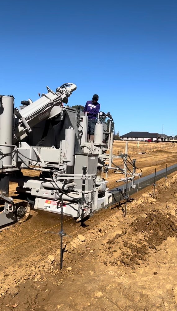 Power Curber laying a continuous concrete curb and gutter along a new development